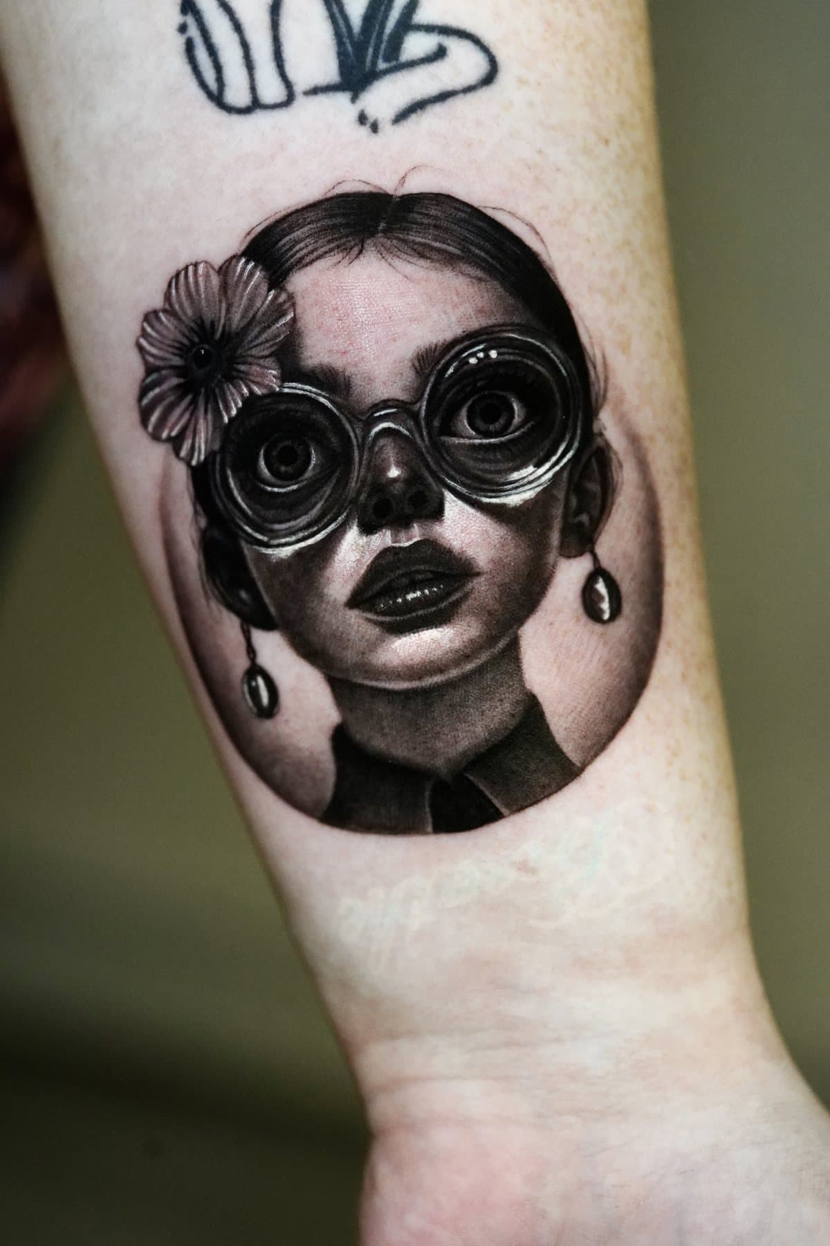Close-up of the award-winning black and grey micro portrait of a girl in round goggles with a flower in her hair