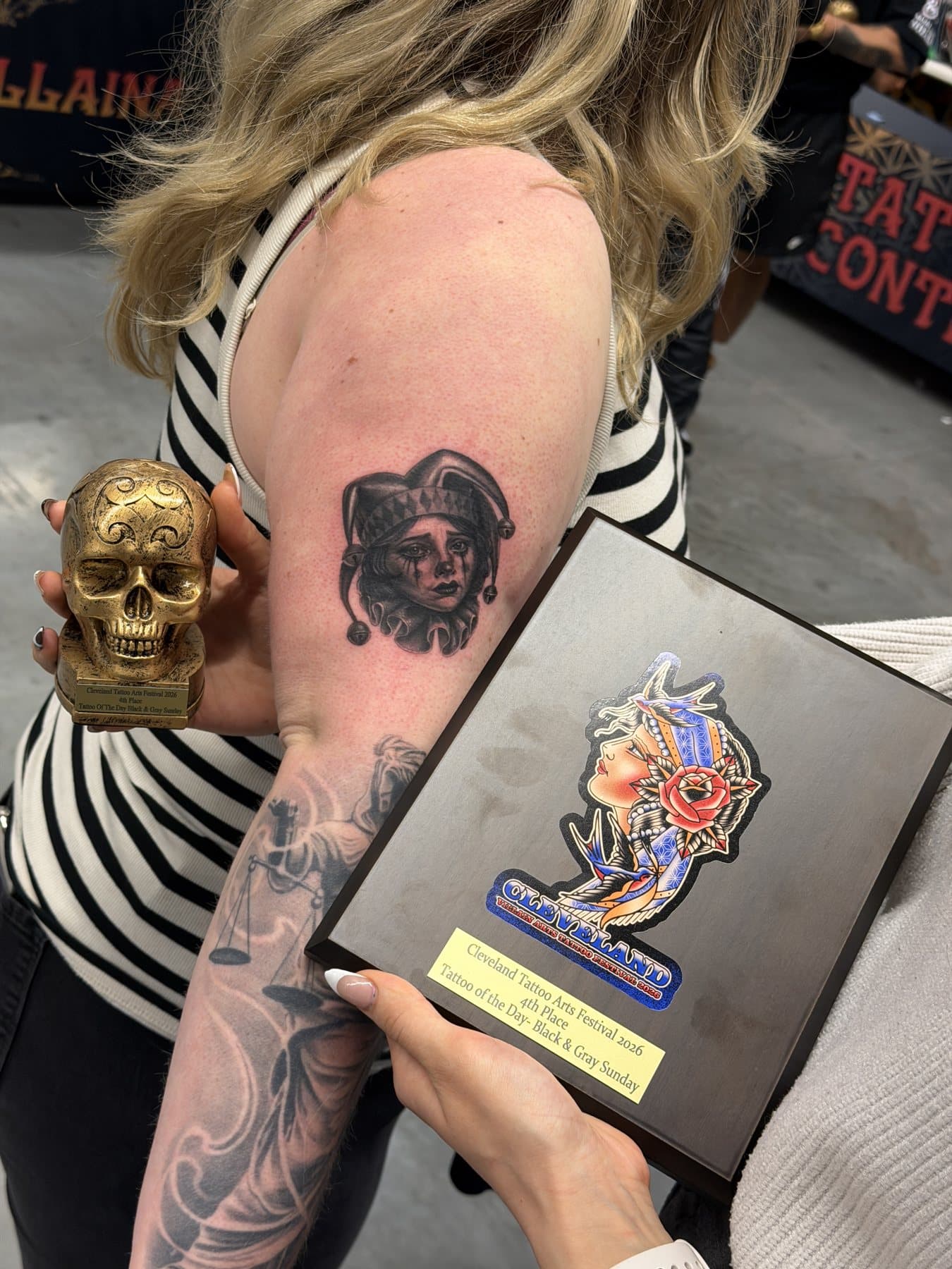 The jester tattoo beside the 4th place Tattoo of the Day Black & Gray Sunday plaque and skull trophy