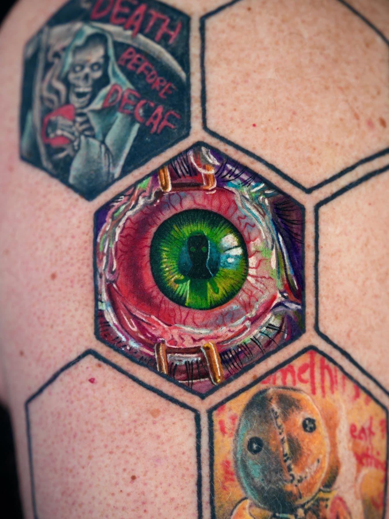 Color realism tattoo of a green eye framed in a hexagon, part of a honeycomb sleeve