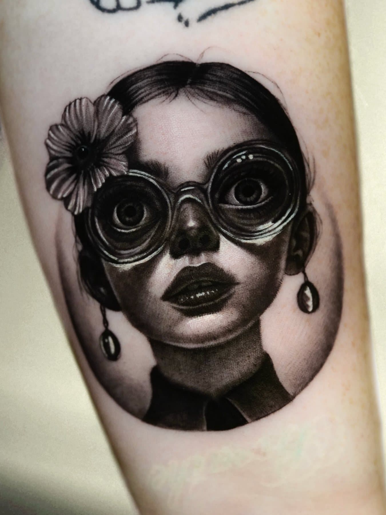 Black and grey micro portrait of a girl wearing round goggles and a flower in her hair