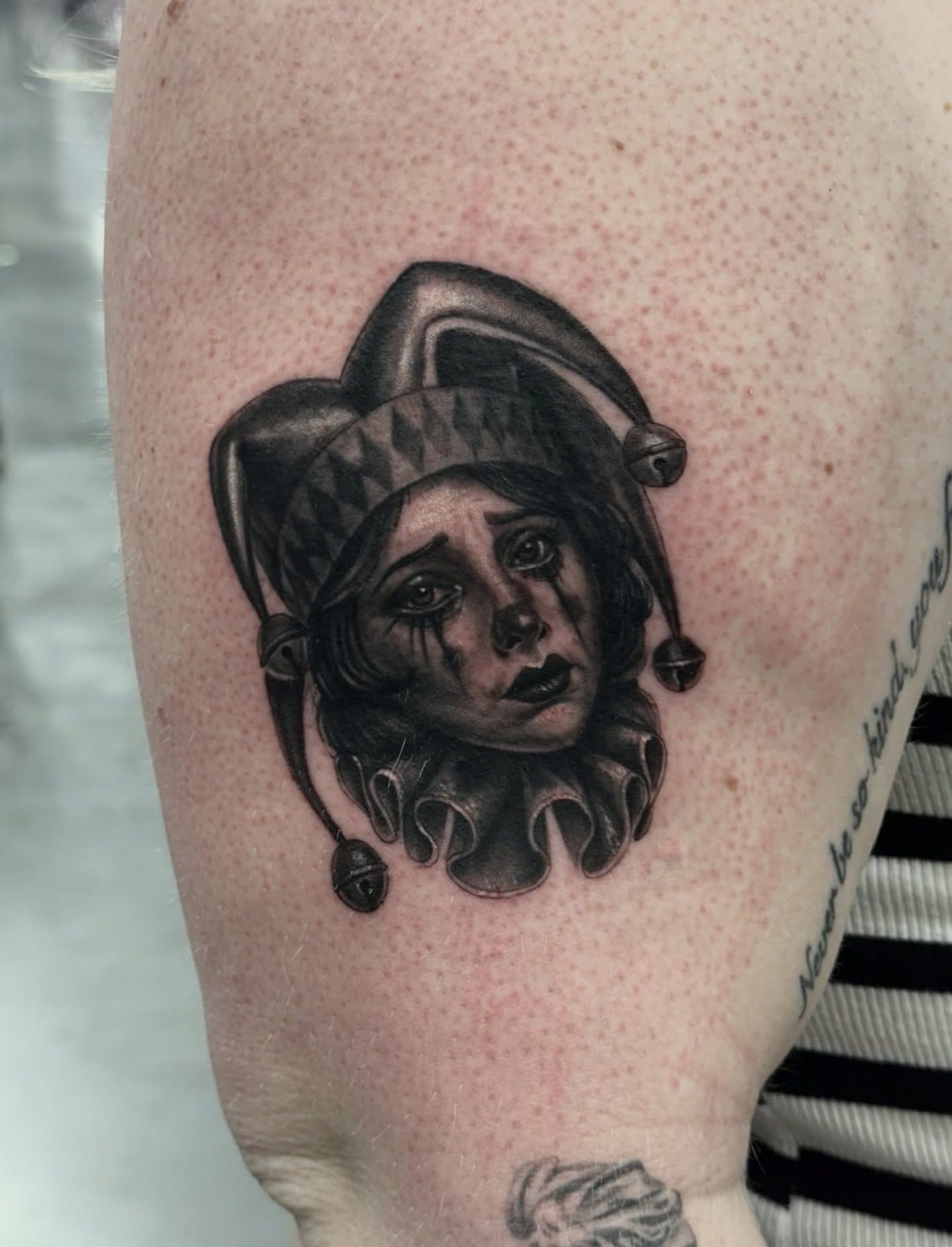 Black and grey micro portrait of a sad jester in a bell hat
